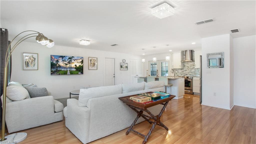 Living room with light wood-type flooring and recessed lighting