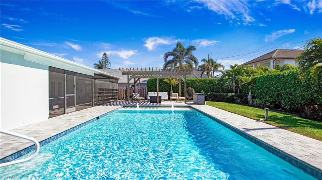 View of swimming pool with a pergola, patio surround, a sunroom, and a fenced backyard