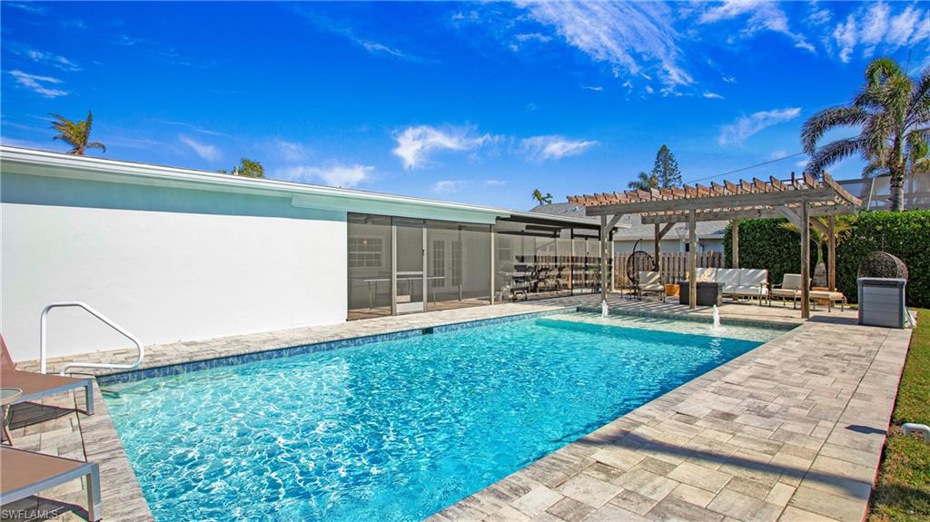 View of pool featuring patio surround, a pergola, and a sunroom