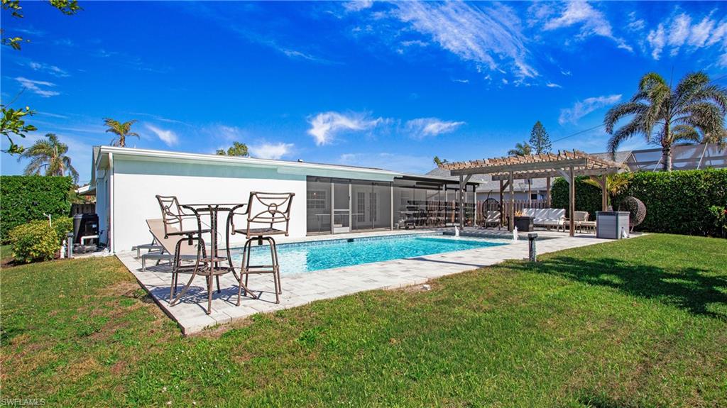 View of pool with patio surround, a pergola, a lawn, a sunroom, and outdoor seating