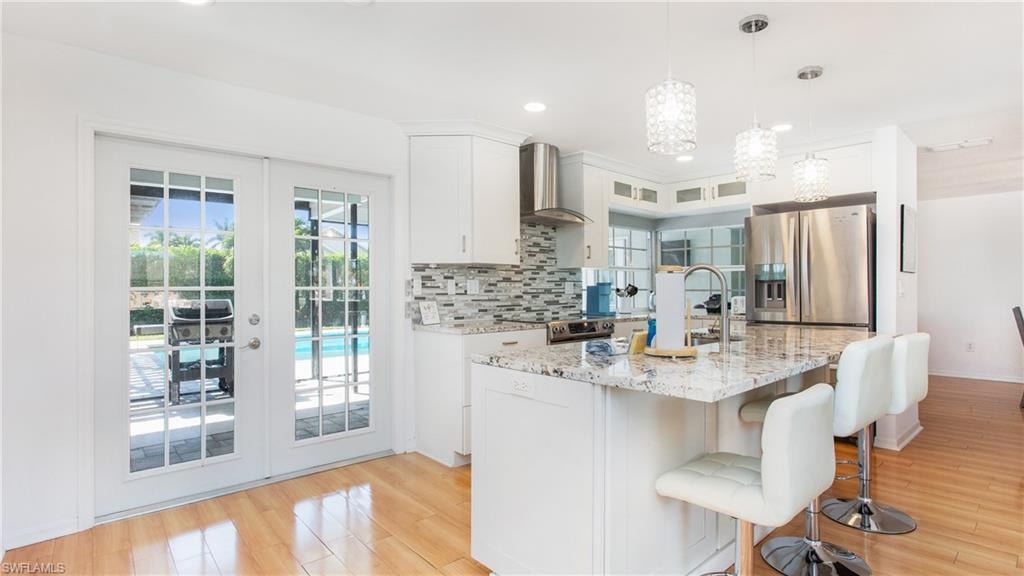 Kitchen with french doors, white cabinetry, light stone counters, and stainless steel appliances