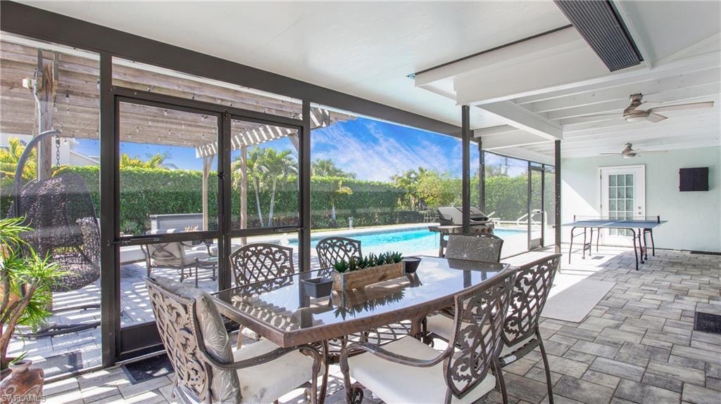 Sunroom / solarium featuring a ceiling fan, outdoor dining area, and a patio