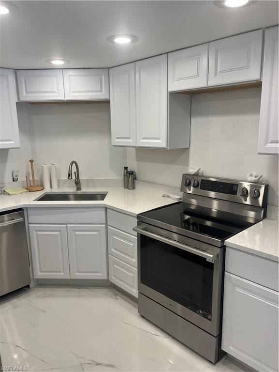 Kitchen with stainless steel range, dishwashing machine, light stone counters, white cabinets, and recessed lighting