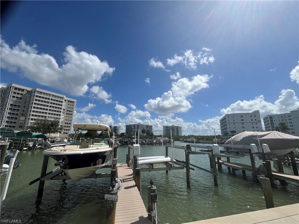 Dock area featuring boat lift, a water view, and a view of city