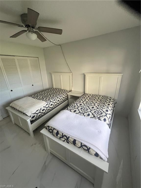 Bedroom with a ceiling fan, marble finish flooring, and a closet