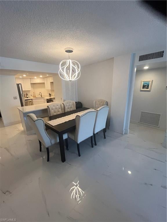 Dining space with hanging lights, a textured ceiling, and light marble finish floors