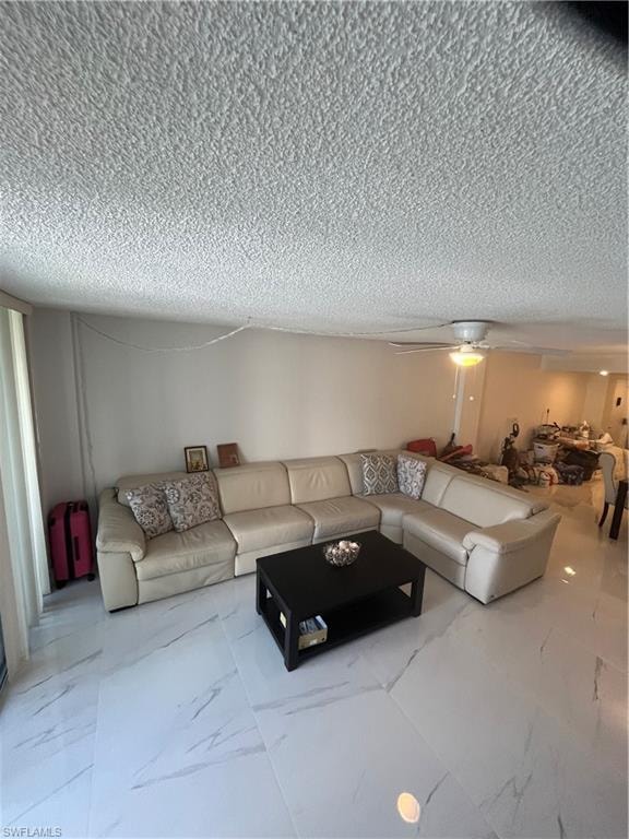 Living room with ceiling fan, a textured ceiling, and light marble finish flooring
