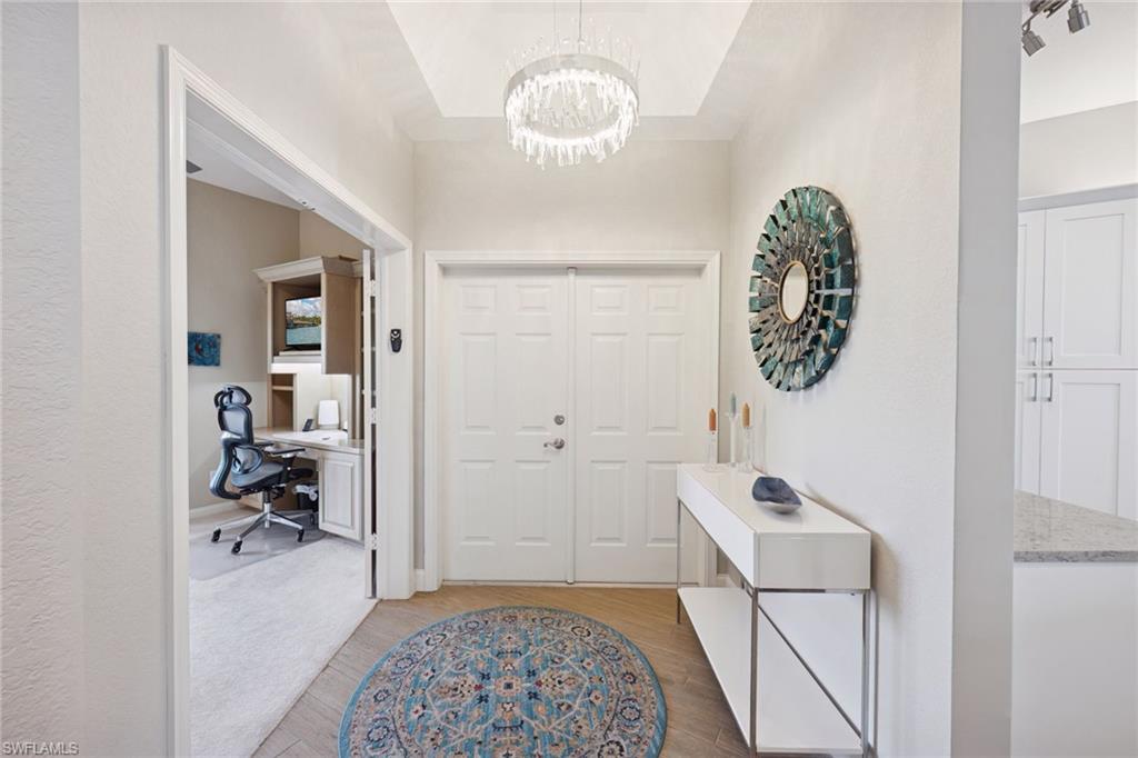Entrance foyer with suspended lighting and light wood flooring