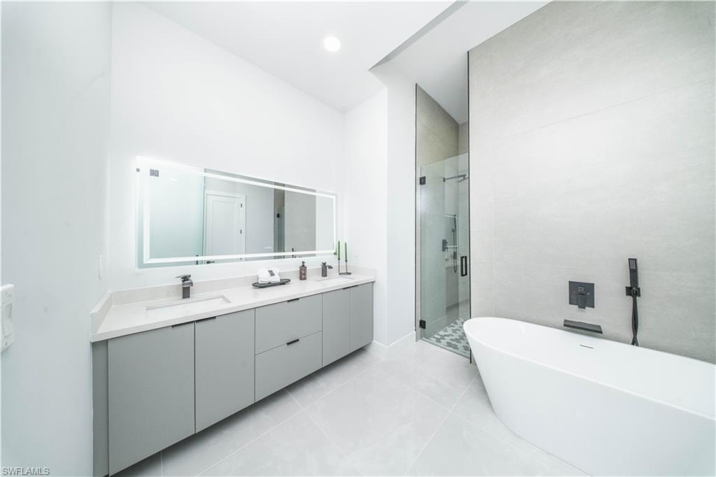Full bathroom featuring a shower stall, double vanity, a soaking tub, light tile patterned floors, and recessed lighting