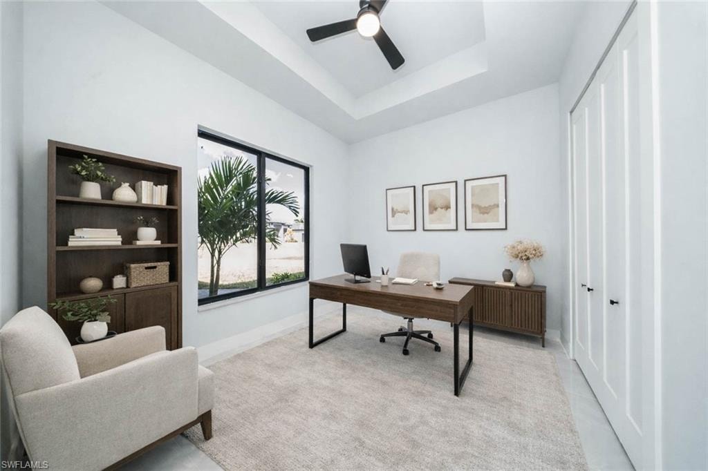 Home office with a ceiling fan and a tray ceiling