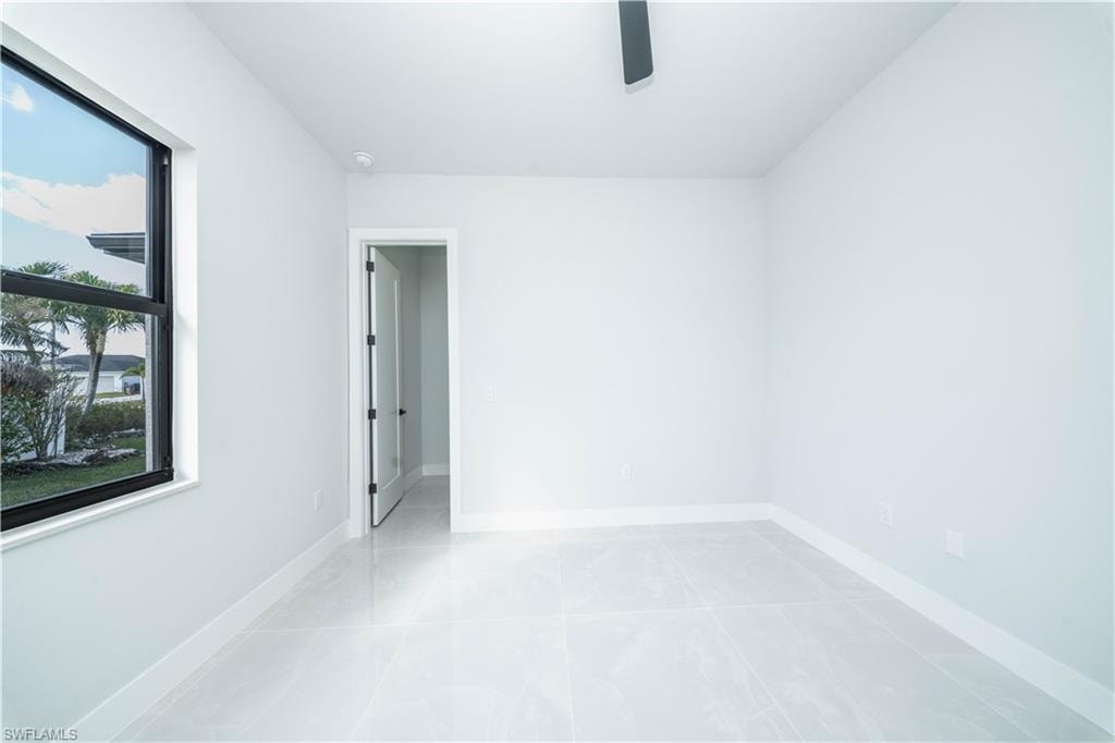 Empty room with ceiling fan and light tile patterned flooring
