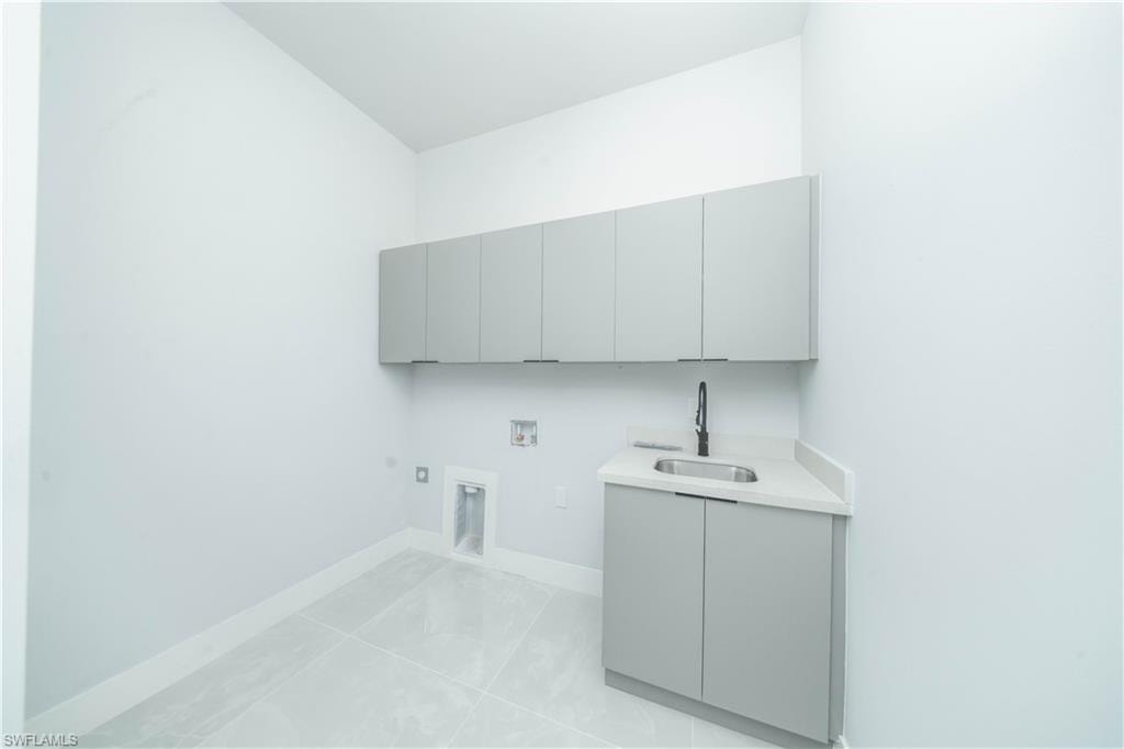 Laundry room featuring gas dryer hookup, hookup for a washing machine, cabinet space, and light tile patterned flooring