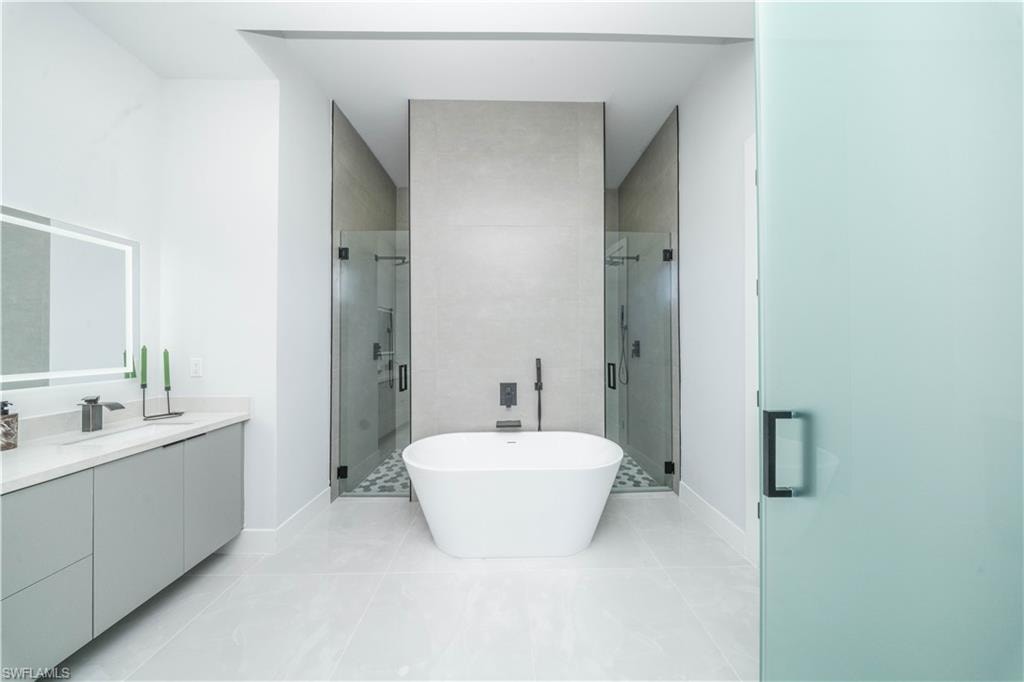 Bathroom featuring a soaking tub, a stall shower, vanity, and light tile patterned floors