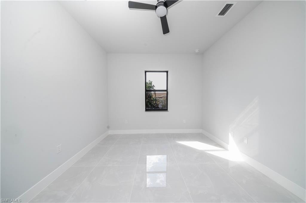 Spare room with ceiling fan and baseboards