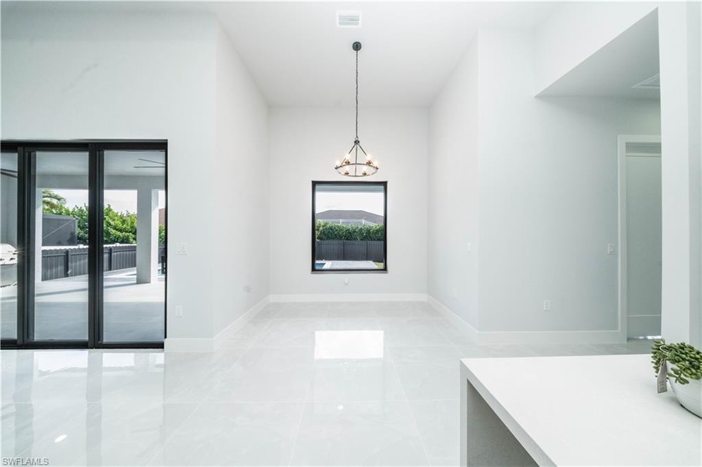 Unfurnished dining area with hanlging lights and baseboards