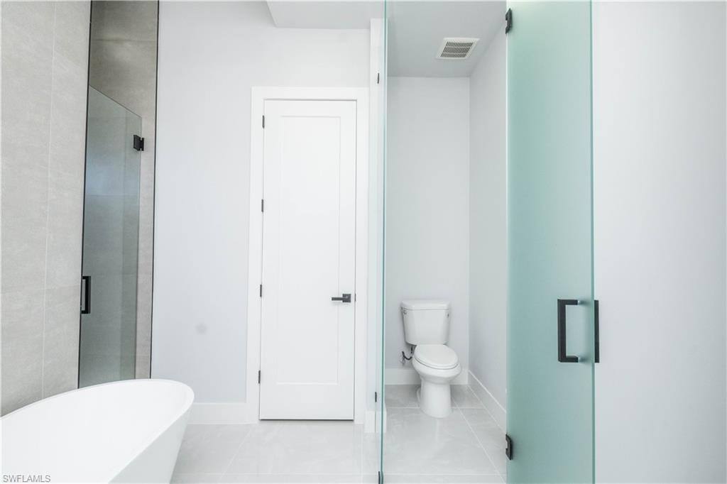 Bathroom featuring light tile patterned floors, a freestanding bath, and a shower stall