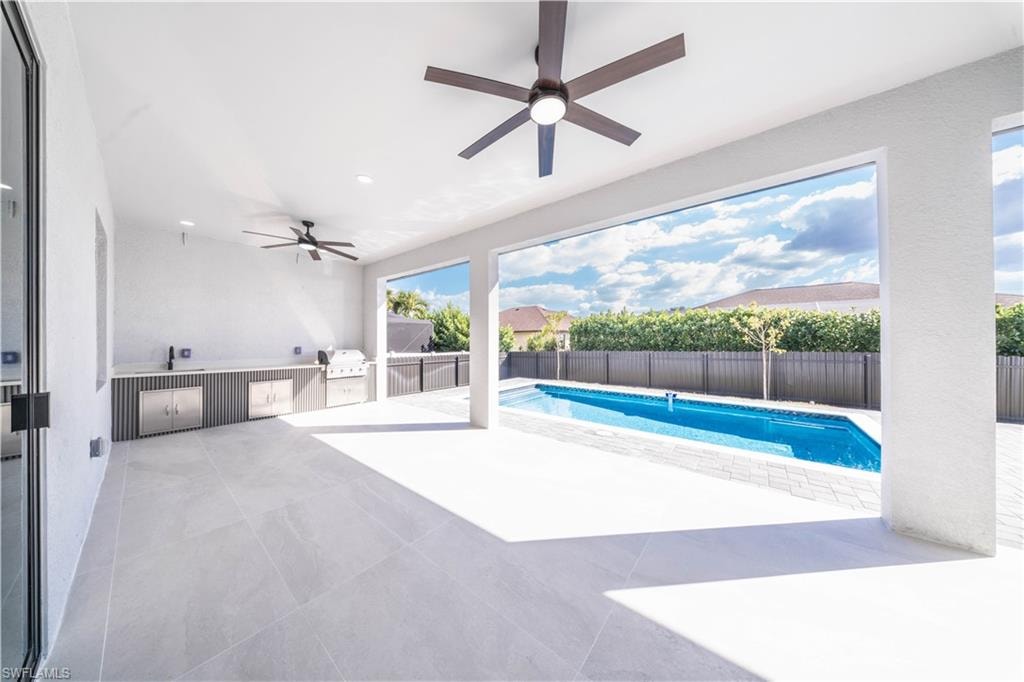 Fenced backyard featuring a patio, a ceiling fan, and an outdoor kitchen and area to lounge