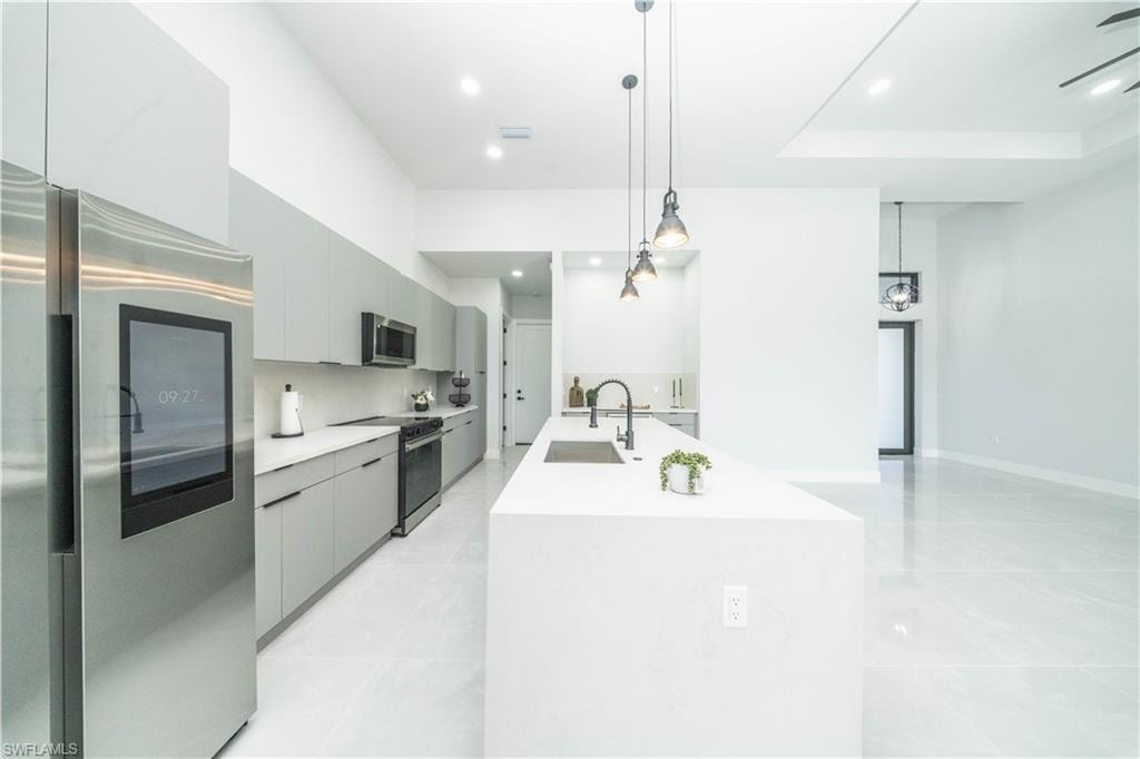 Kitchen with stainless steel appliances, gray cabinets, decorative light fixtures, and modern cabinets
