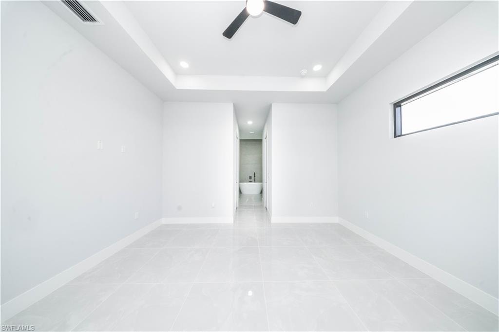 Empty room featuring ceiling fan, a raised ceiling, and recessed lighting