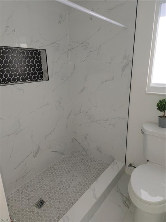 Full bath featuring a marble finish shower and marble look tile flooring