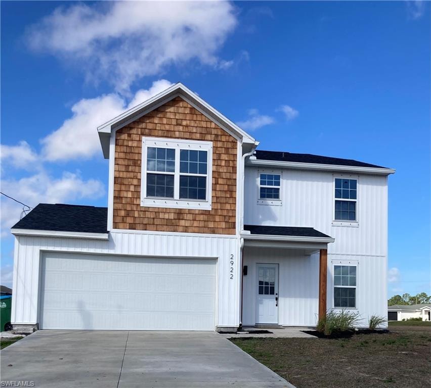 View of front of house with concrete driveway, roof with shingles, an attached garage, and board and batten siding and cedar shakes.