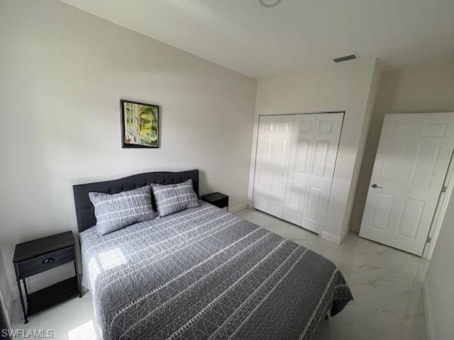 Bedroom featuring a closet and light marble finish floors