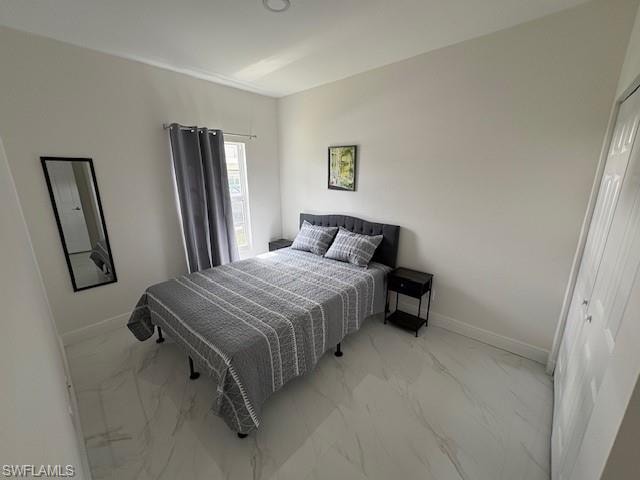 Bedroom with light marble finish floors and a closet
