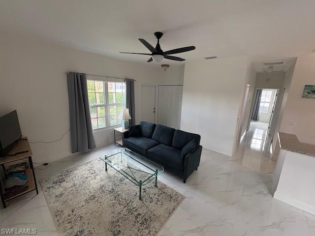 Living area featuring a ceiling fan and light marble finish floors