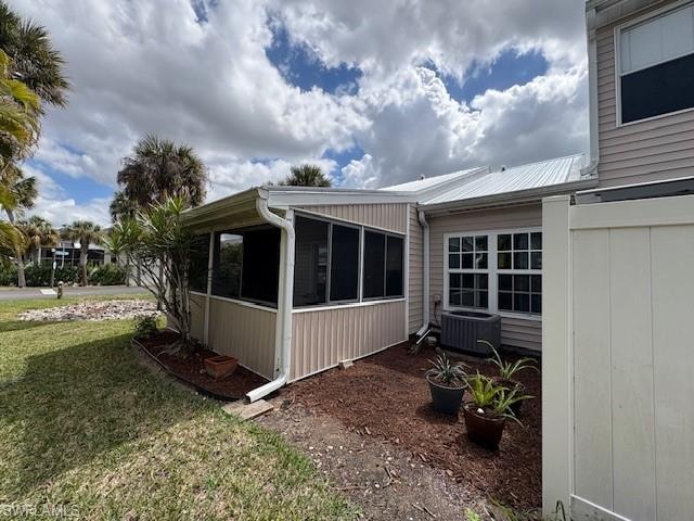 View of property exterior featuring a sunroom and a yard