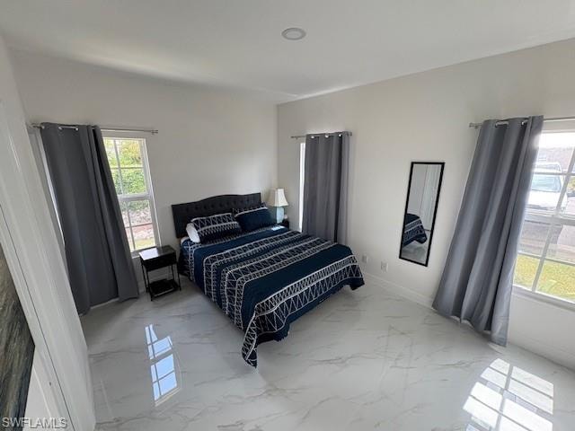 Bedroom featuring light marble finish floors and baseboards