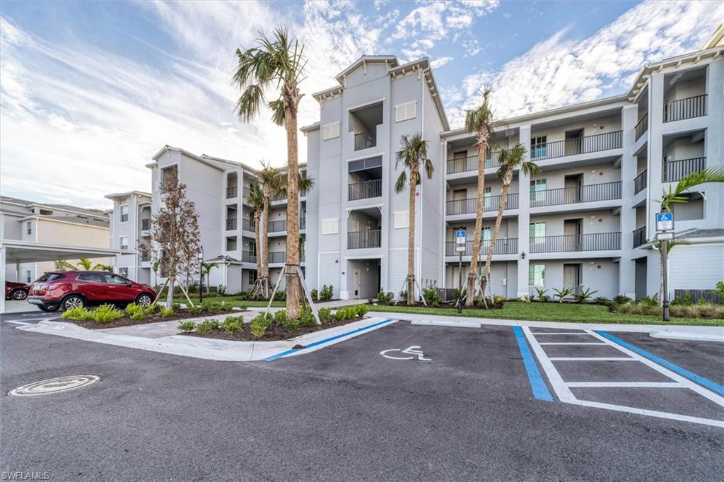 View of apartment building / complex featuring uncovered parking
