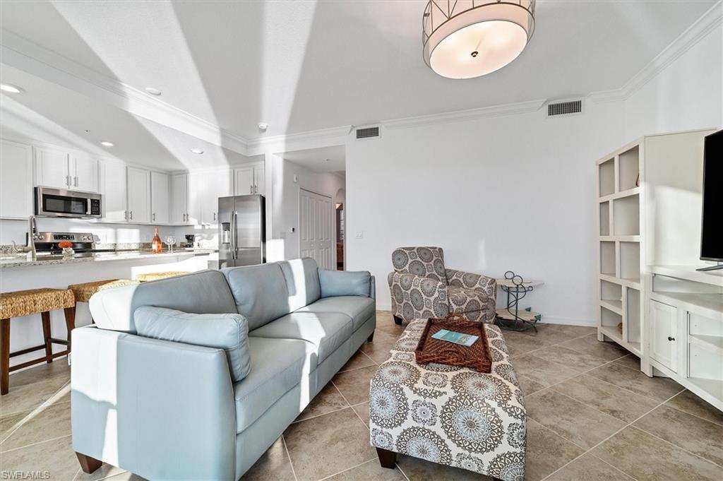 Living area with crown molding, light tile patterned floors, vaulted ceiling, and recessed lighting