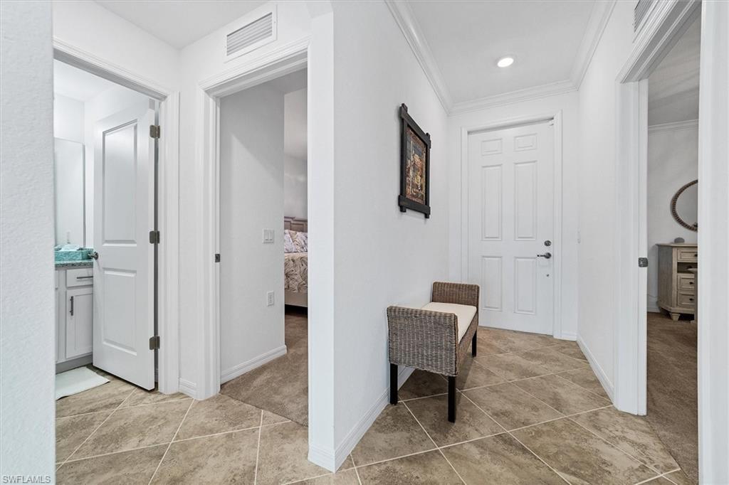 Hall with light tile patterned floors and crown molding