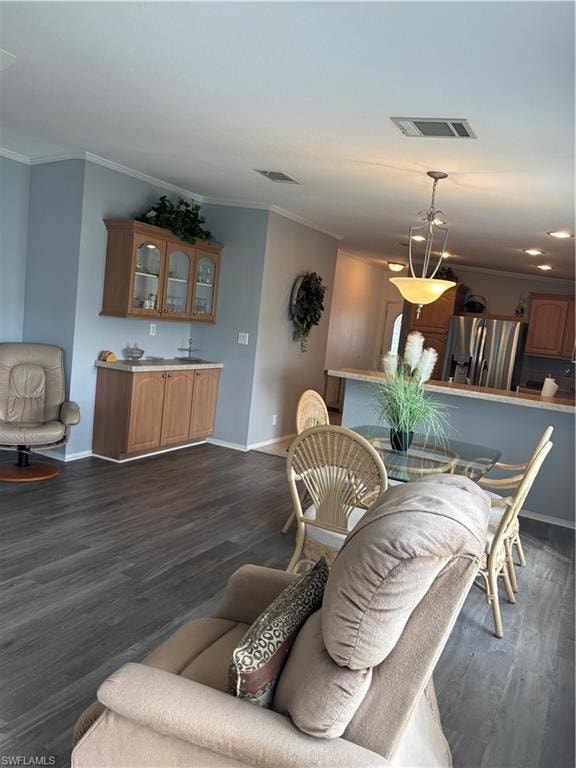 Dining space featuring ornamental molding and dark wood-style flooring