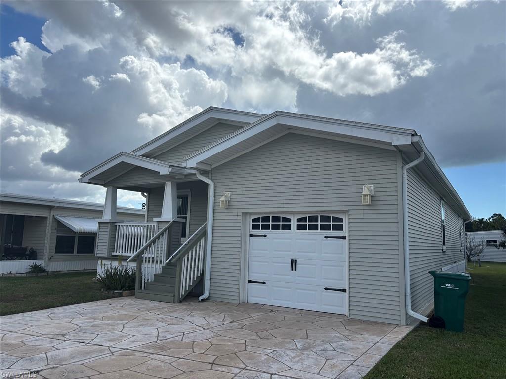 View of front of property featuring a garage, driveway, a front yard, and covered porch