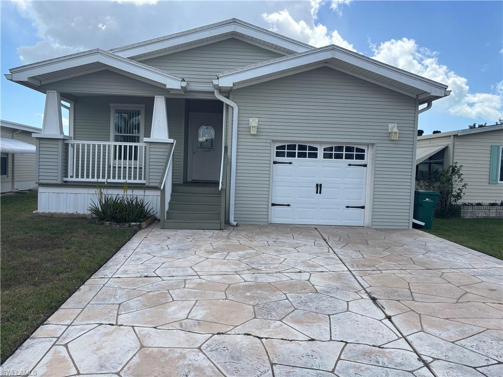 View of front of home with covered porch, a garage, a front yard, and driveway