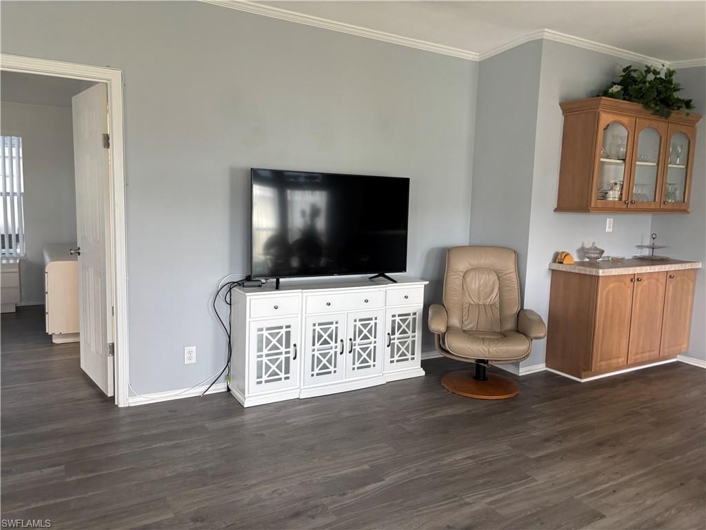 Sitting room with ornamental molding and dark wood finished floors
