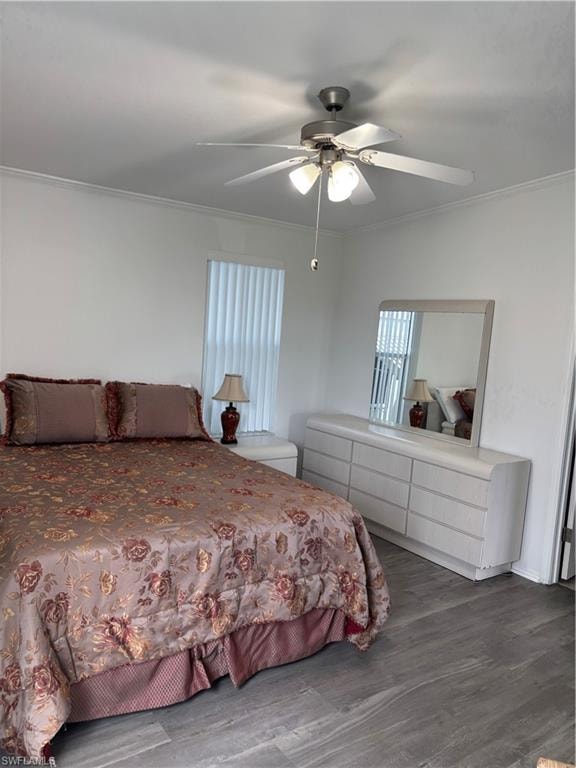 Bedroom with dark wood-type flooring, a ceiling fan, multiple windows, and ornamental molding