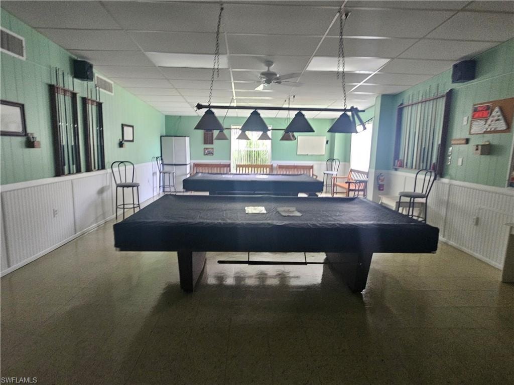 Recreation room with a drop ceiling, wainscoting, wooden walls, billiards table, and ceiling fan
