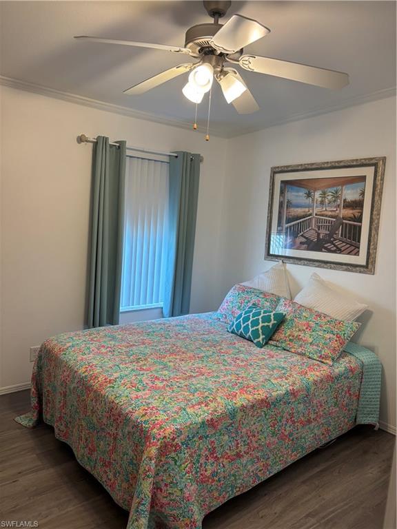 Bedroom with dark wood finished floors, a ceiling fan, and ornamental molding