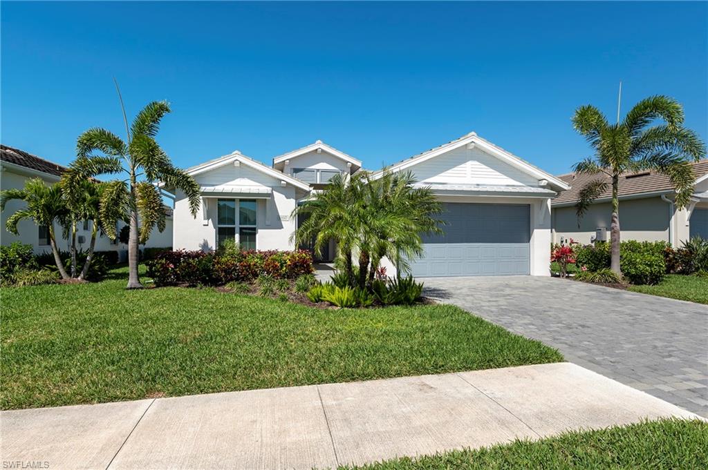 Ranch-style house featuring a front lawn, a garage, decorative driveway, and stucco siding