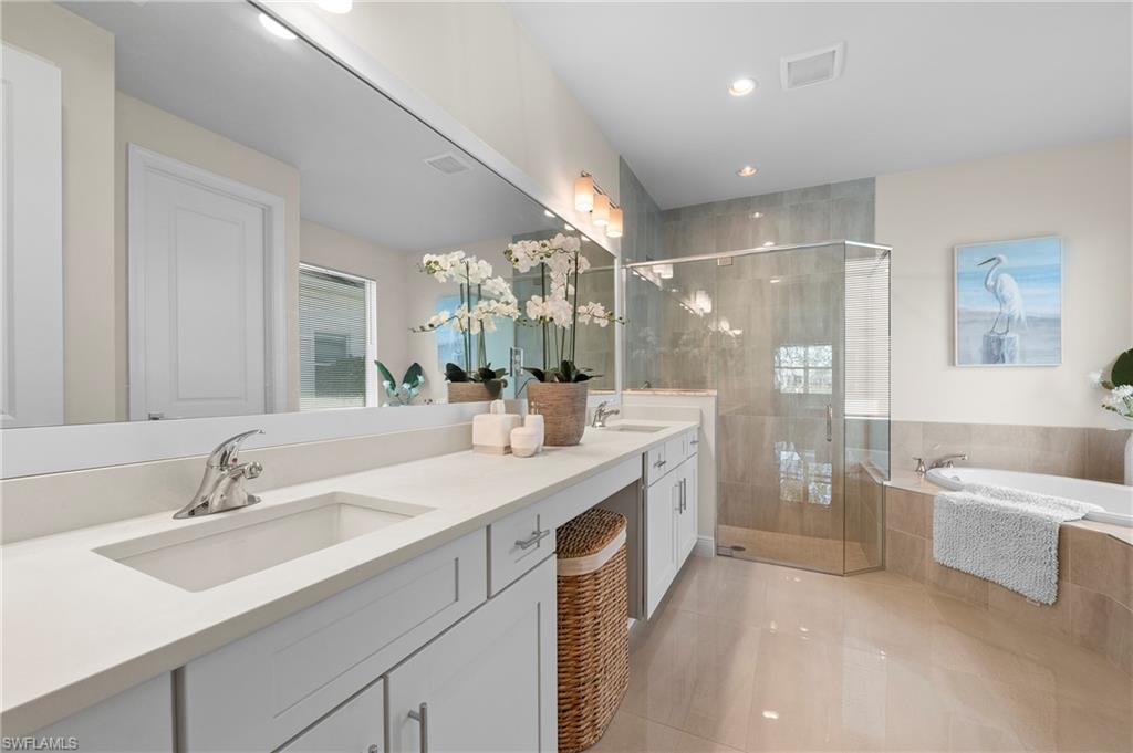 Bathroom featuring a shower stall, double vanity, a bath, light tile patterned flooring, and recessed lighting