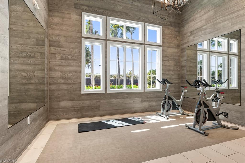 Workout area with hanging lights, a high ceiling, and wood walls