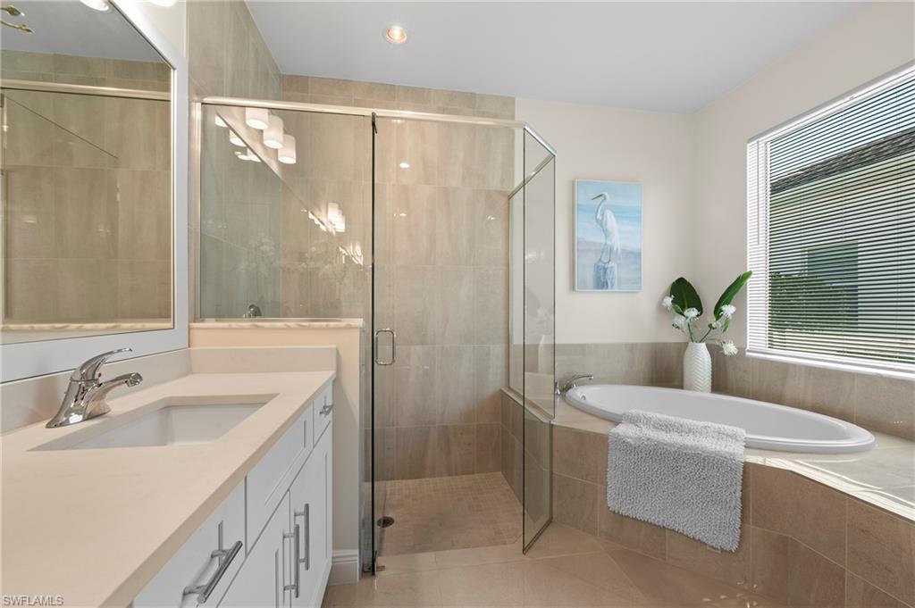 Full bathroom featuring vanity, a shower stall, a garden tub, and light tile patterned floors