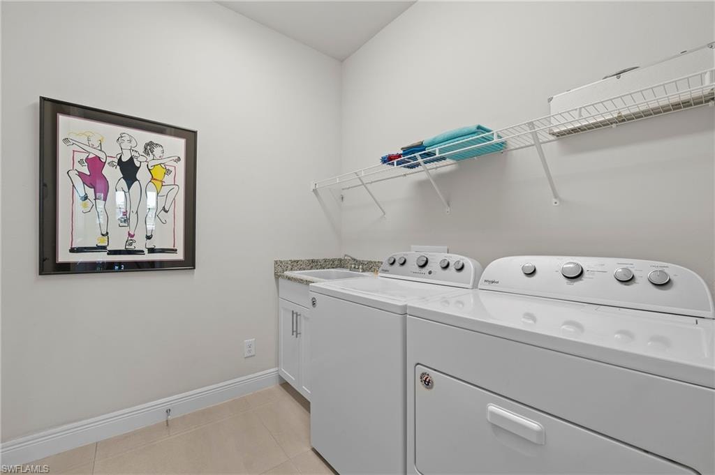 Laundry room featuring light tile patterned floors, washing machine and clothes dryer, and cabinet space