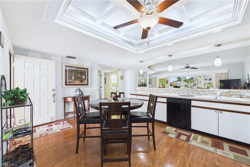 Kitchen with light countertops, black dishwasher, light wood finished floors, pendant lighting, and coffered ceiling
