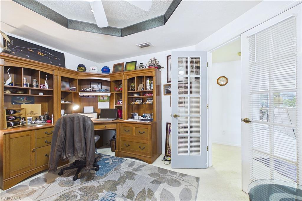 Home office with light colored carpet and a ceiling fan