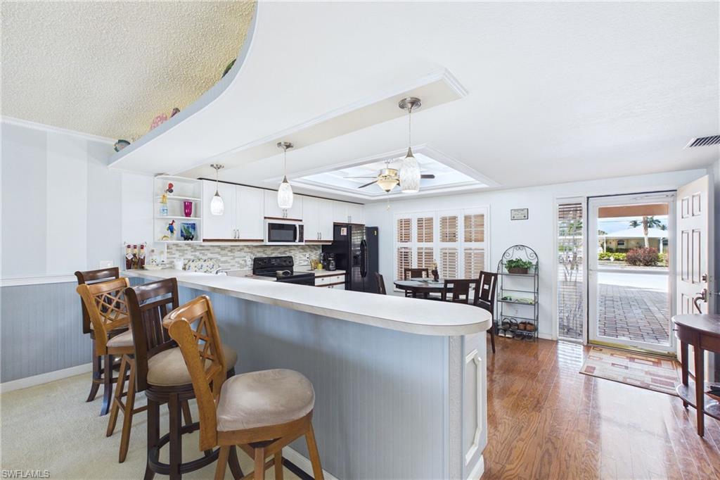Kitchen with light countertops, a kitchen breakfast bar, a peninsula, a ceiling fan, and white cabinetry