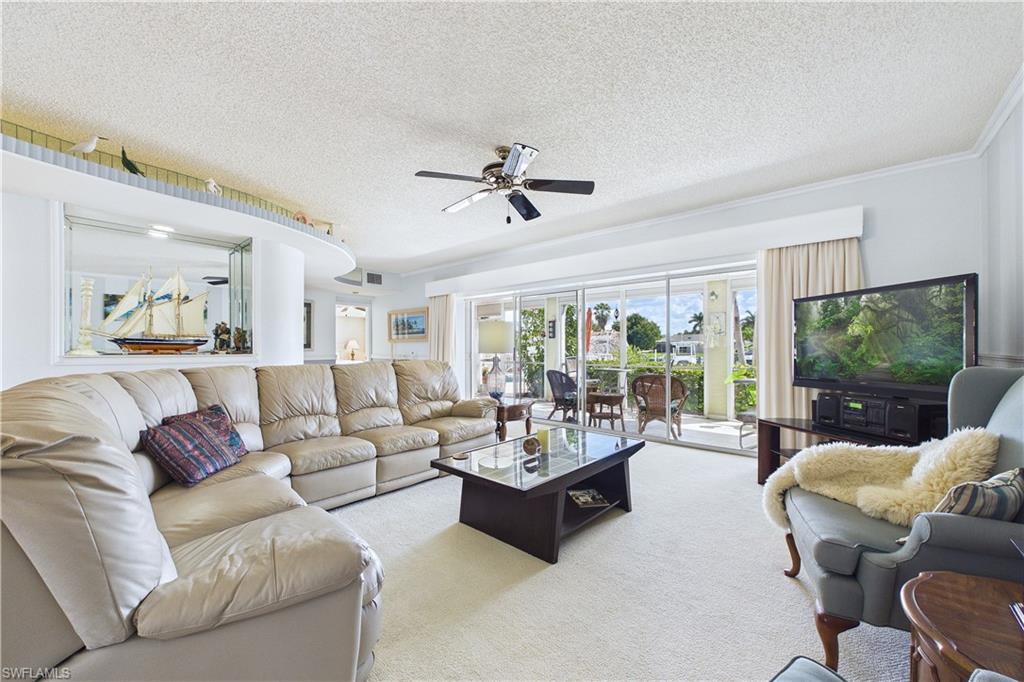 Living room featuring a ceiling fan, a textured ceiling, and light carpet