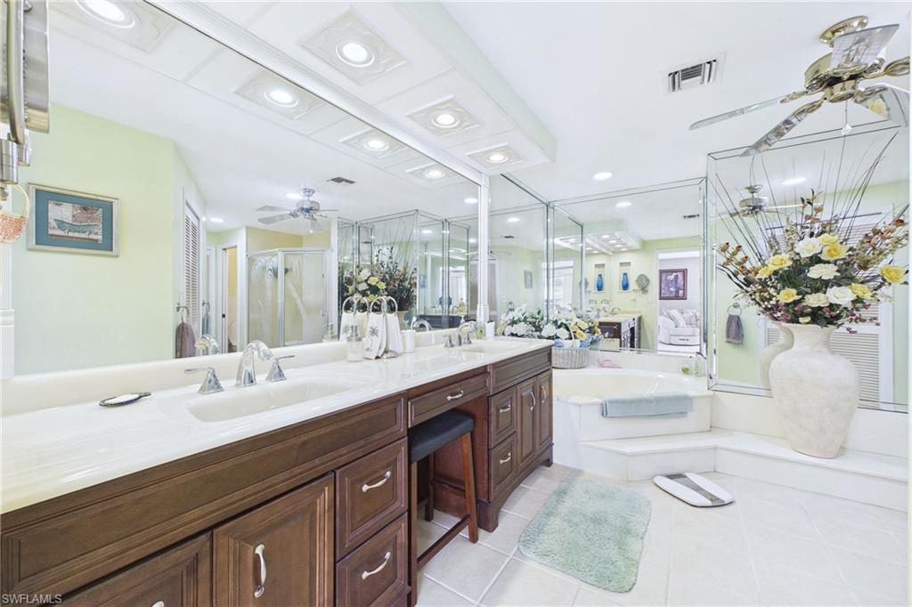 Primary Bathroom with a ceiling fan, a stall shower, double vanity, light tile patterned floors, and a bath